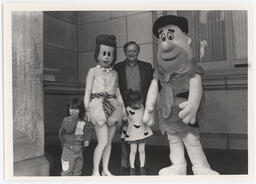 Rep. Kenneth Brandt and two children standing with costumed characters Fred and Wilma Flintstone on the capitol steps.