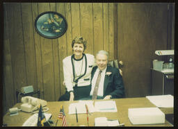 Rep. Burns seated at his office desk with his administrative assistant beside him