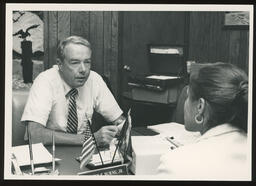 Rep. Burns at his office desk speaking with a staff member