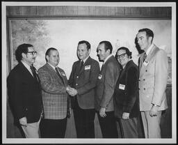 Rep. Edward Burns stands in front of a painting with a group of men.