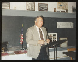 Undated, Rep. Thomas Tangretti speaking in a classroom with a chalk board in the background.