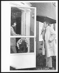 Jim Kelly at door with umbrella front