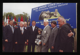 A group photograph in front of the construction sign for the Veterans Memorial at Indiantown Gap National Cemetery