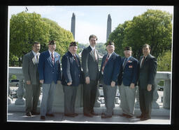 Representatives and Veterans at the back of the Capitol Building near the water fountain.