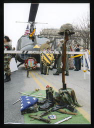 A memorial to fallen Vietnam War soldiers set up in front of a stationary helicopter known as "America's Huey - 091."